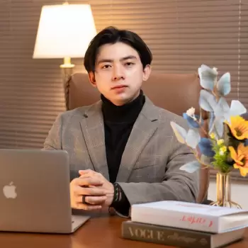 pria muda, tampan, profesional, jas, kemeja turtleneck, duduk, meja, laptop, buku, bunga, lampu meja, kantor, bisnis, modern, percaya diri, formal, akademis, eksekutif, ceo, pengusaha, muda, asia, muda profesional, gaya, elegan, rapi, serius, berwajah datar, berkerah tinggi, berkacamata hitam