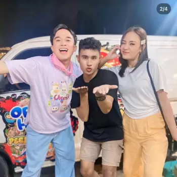 tiga orang, pria, wanita, tersenyum, tertawa, gembira, bahagia, berpose, bersama, teman, komunitas, malam, luar ruangan, latar belakang van, mobil, makanan, jajan, minuman, ceria, warna-warni, kaus, celana, rambut pendek, gaya kasual, muda, segar, ramah, mengundang, candid, informal