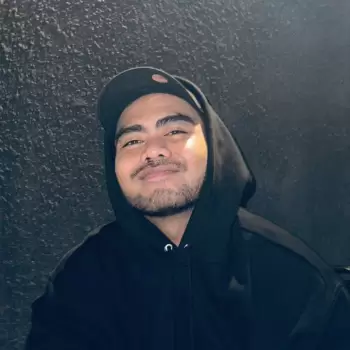 pria, laki-laki, muda, dewasa, tampan, berjanggut, berkulit sawo matang, tersenyum, bahagia, santai, casual, memakai topi, memakai hoodie, hoodie hitam, topi hitam, gelap, latar belakang gelap, informal, potret, wajah, mata, hidung, bibir, rambut, gaya, keren, percaya diri, modern, urban, close-up