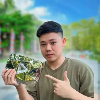 youtuber, pria, penghargaan, tombol play, silver play button, konten kreator, merayakan, pencapaian, sukses, kebahagiaan, bangga, hadiah, hadiah emas, hadiah perak, gaya, santai, di luar ruangan, taman, jalan, pohon, langit biru, awan, latar belakang buram, terlihat dekat, menunjuk, tersenyum, muda, indonesia, asia.