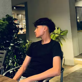 pria, muda, remaja, santai, duduk, kaus hitam, rambut berantakan, sisi, kafe, luar ruangan, malam, lampu, tanaman, daun, kursi, meja, bersandar, tenang, introspektif, potret, candid, fokus, close-up, penampilan, gaya, fashion, kasual, urban, atmosfer, keindahan